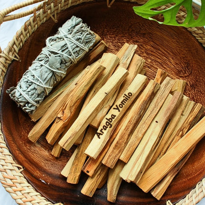 Palo Santo sticks and sage on a wooden plate with a woven mat background